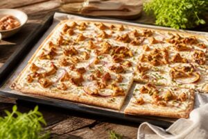 Pfifferling-Flammkuchen vom Blech mit Quark-Öl-Teig, dünn und knusprig gebacken, belegt mit goldgelben Pfifferlingen, Schmand und Röstzwiebeln