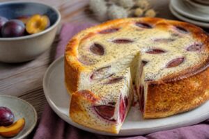 Zwetschgen-Mohn-Käsekuchen ohne Boden, angeschnitten auf einem Holzbrett – cremige Quarkcreme mit Mohnschicht und saftigen Zwetschgen
